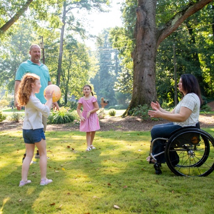 Children playing with a parent in a wheelchair, protected by TruStage AD&D.