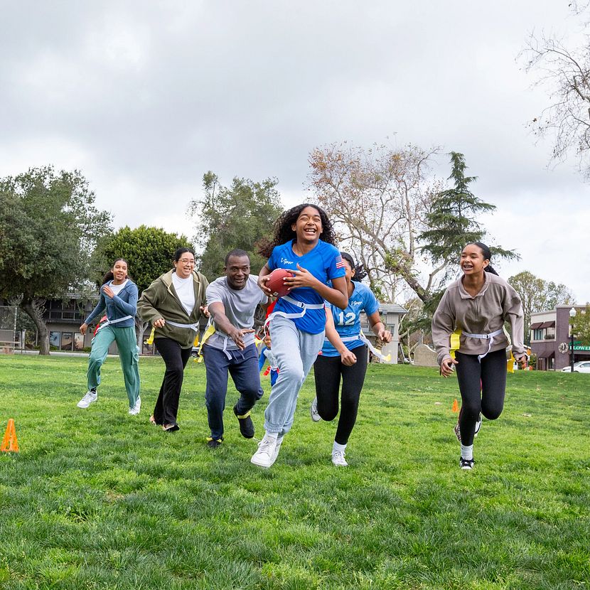 A group of people happily play flag football because of TruStage business solutions life insurance