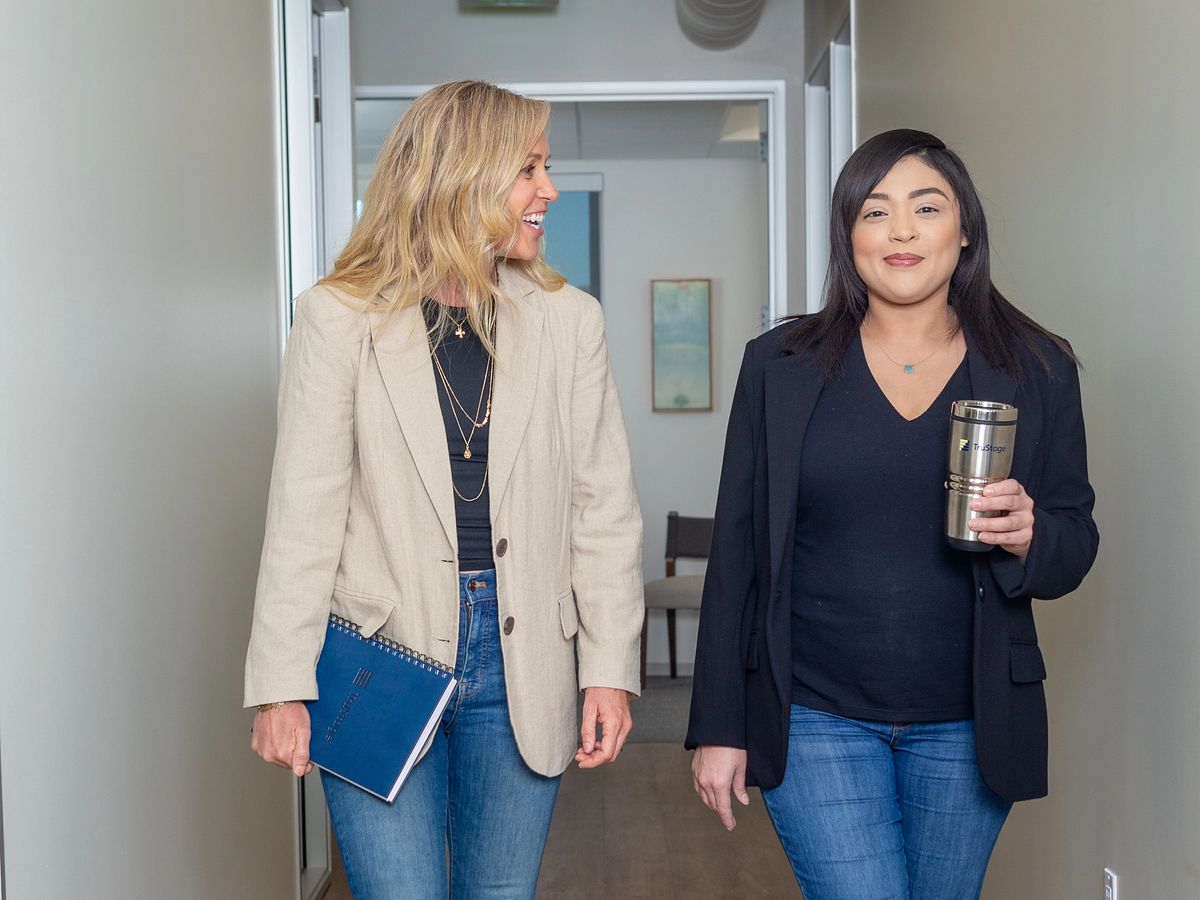 Two women walk down a hallway talking about TruStage workplace solutions