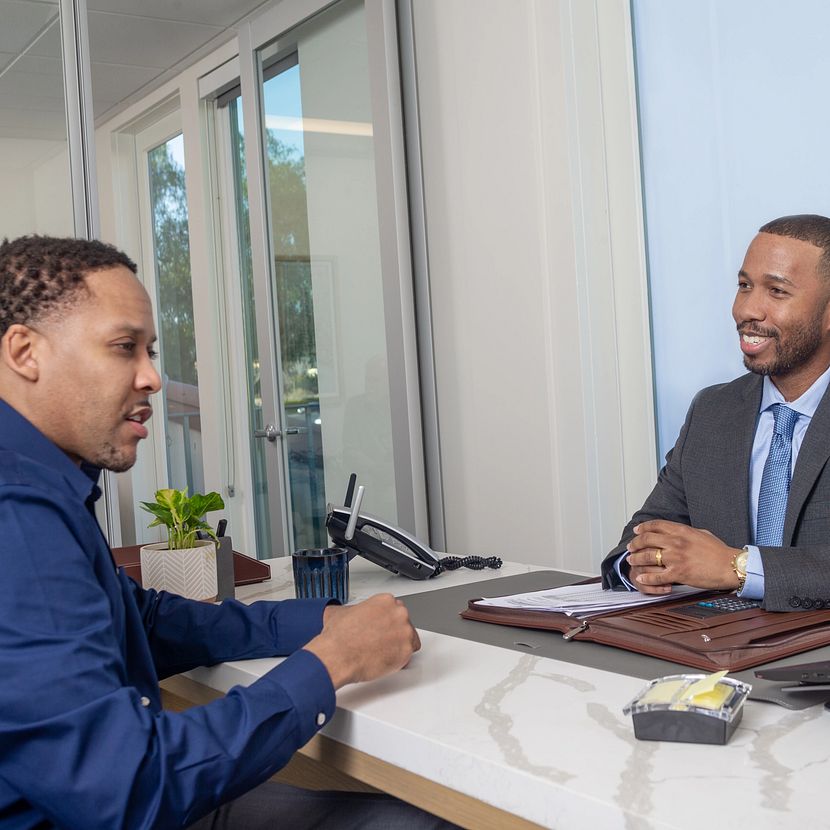 Two people talk across a desk about TruStage workplace solutions individual plan participant