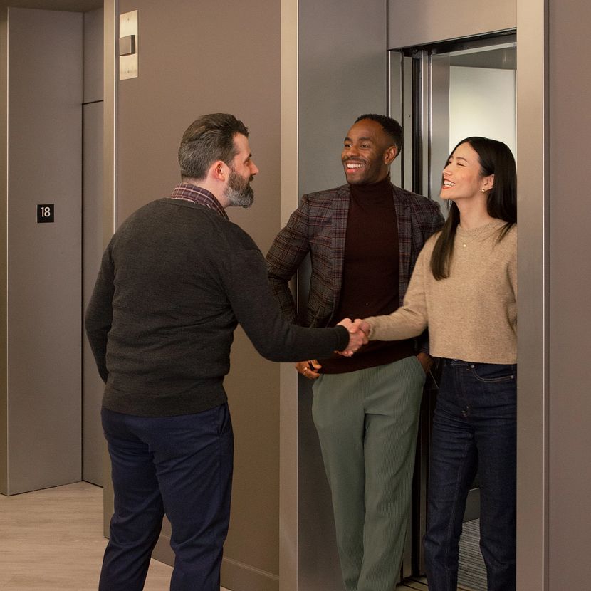 A few people stand near an elevator discussing TruStage speciality commercial programs