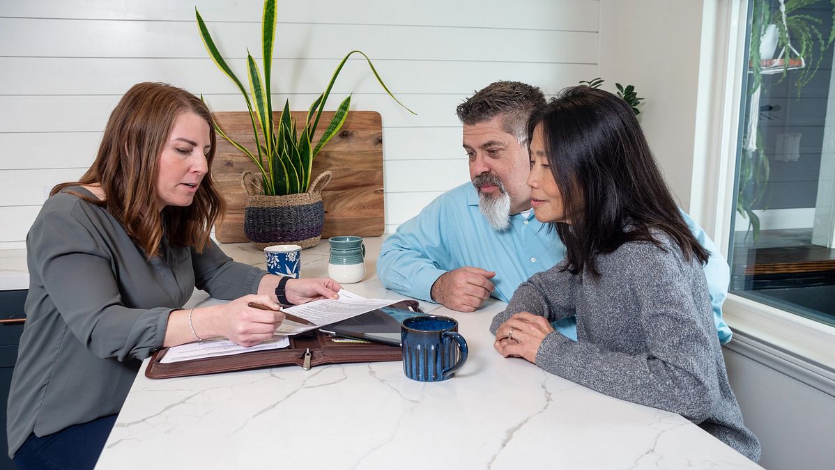 Three people sit around a table talking about TruStage workplace solutions