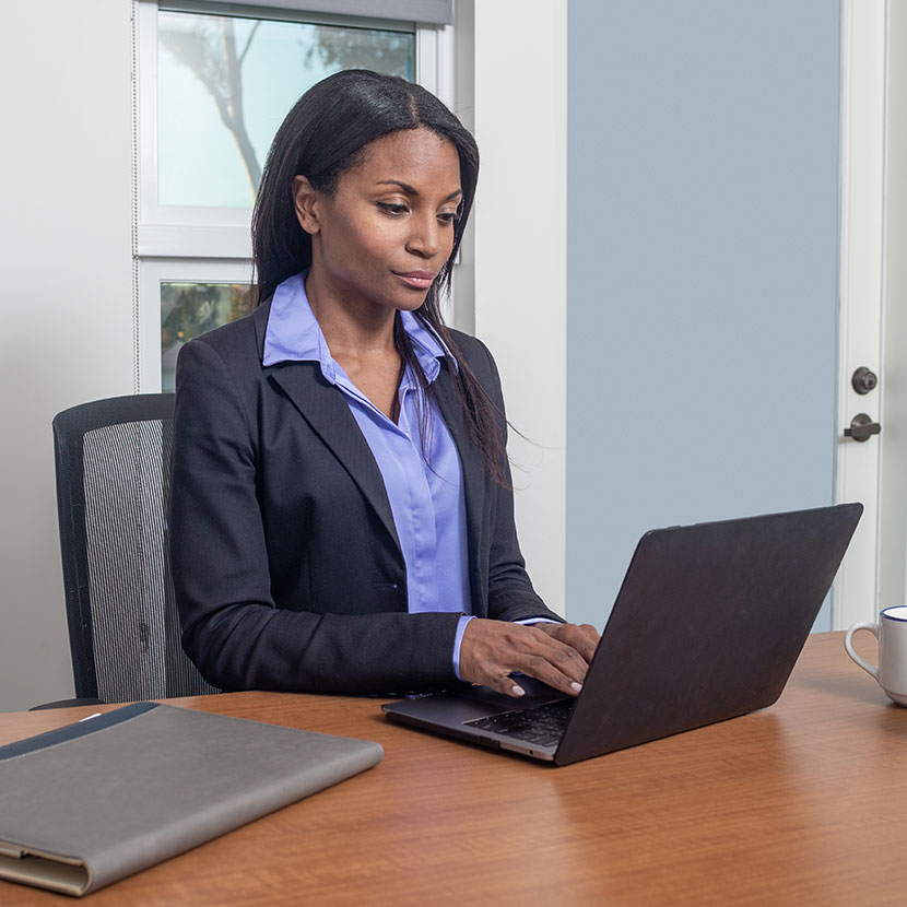 A woman on a laptop reads that TruStage Payment Guard Insurance has been recognized as a Benzinga Global Fintech Awards Runner-Up.