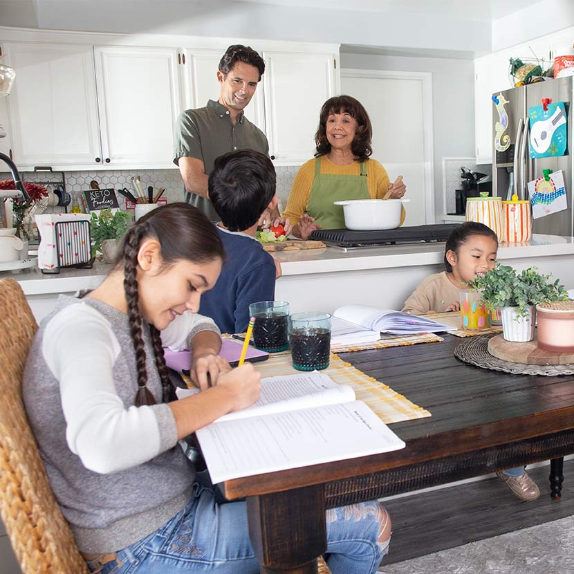 Children complete homework at the kitchen table while their parents cook and discuss findings from the new TruStage survey.
