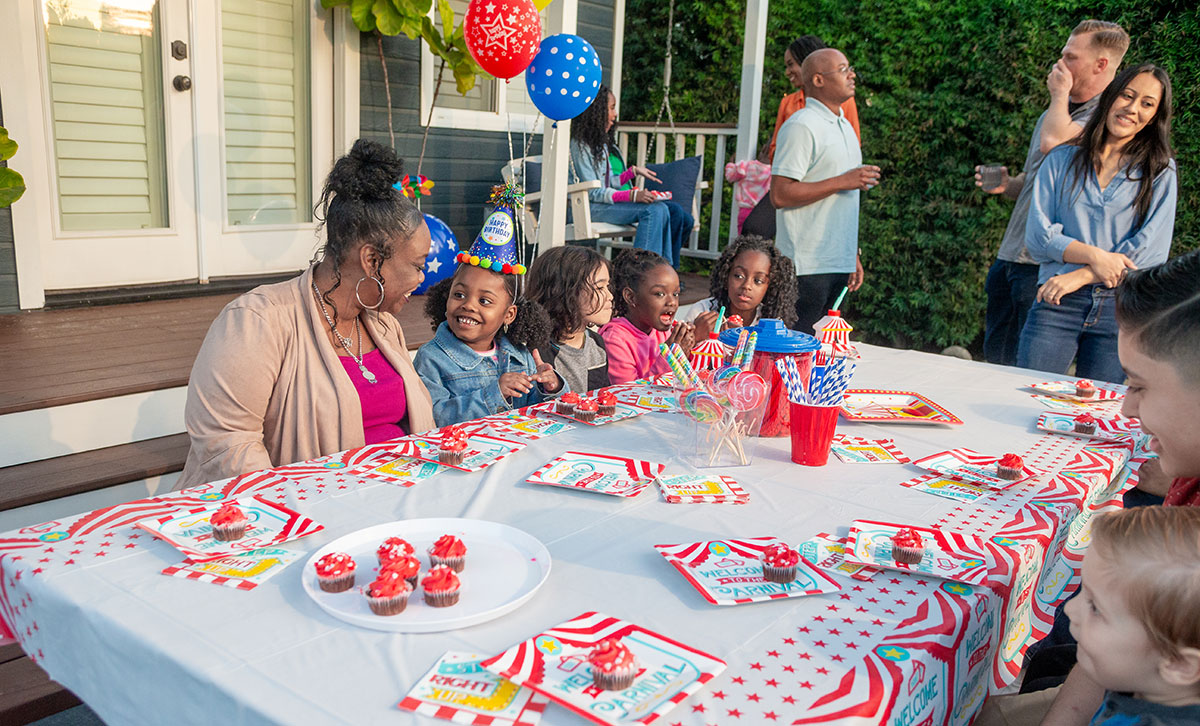 Men, women, and children enjoy a birthday celebration, feeling protected with insurance coverage from TruStage.