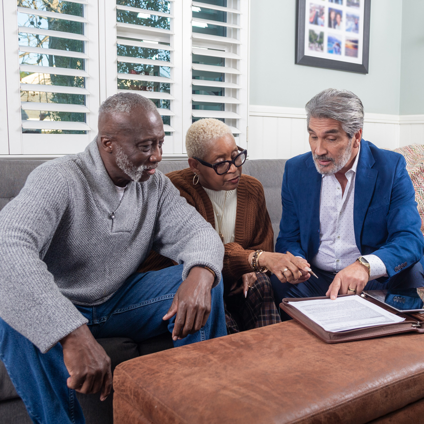 A man and woman sit at a table with a financial professional discussing how TruStage is building brighter financial futures.