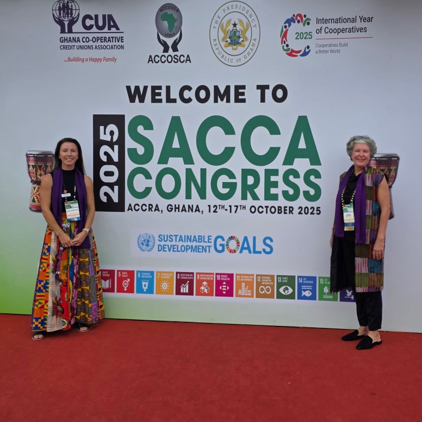 Two financial professionals stand in front of a sign at the SACCA Conference.
