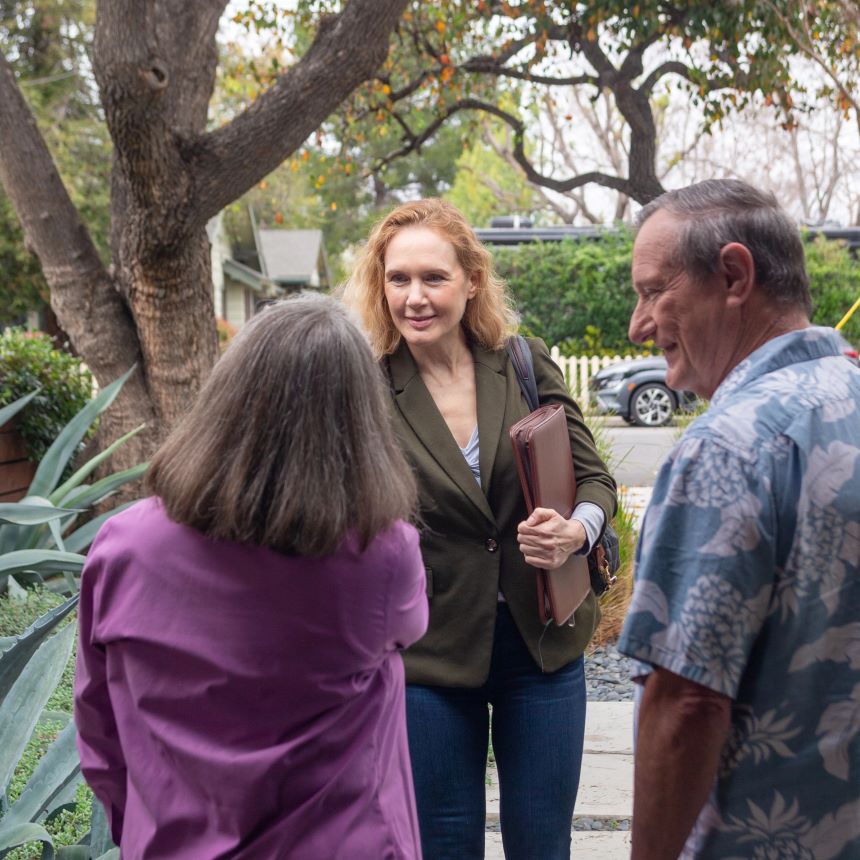 A financial professional shakes hands with a husband and wife while standing on a sidewalk.