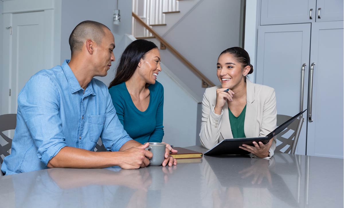 A man and woman sit at a table with a financial professional discussing how TruStage is building brighter financial futures.