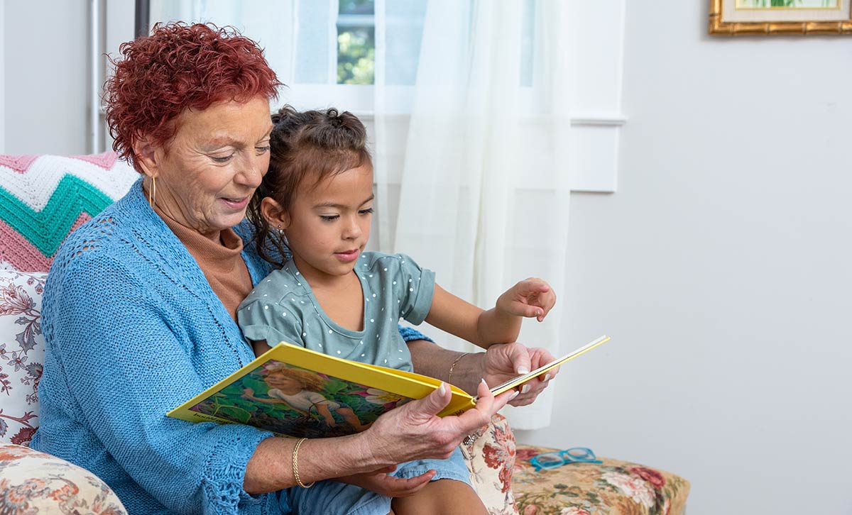 A woman, reading to a young girl, has peace of mind that comes from being better protected by an annuity.