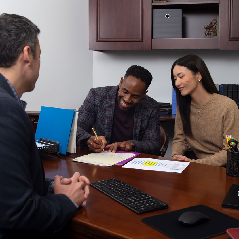 A couple signing TruStage business documents together in an office