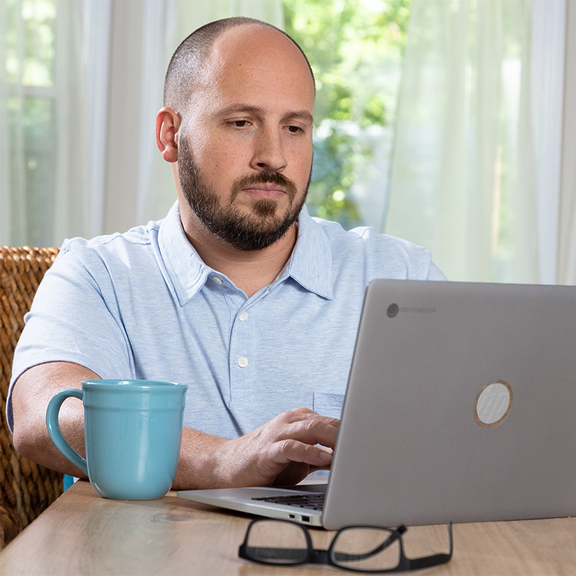 Man sitting at table with coffee and laptop