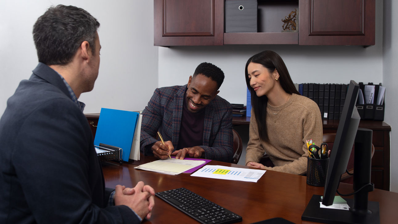 A couple signing TruStage business documents together in an office