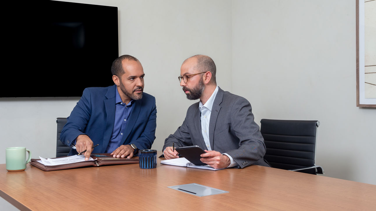 Two people sitting at a table talking about TruStage program management