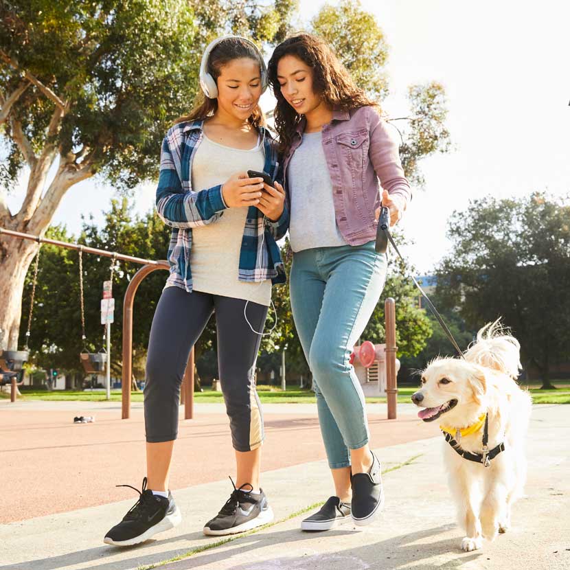 Two active young women walk their large dog after completing a TruStage insurance application.