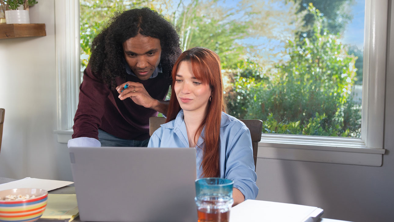 Two people learn about TruStage Payment Guard cash advance on a laptop