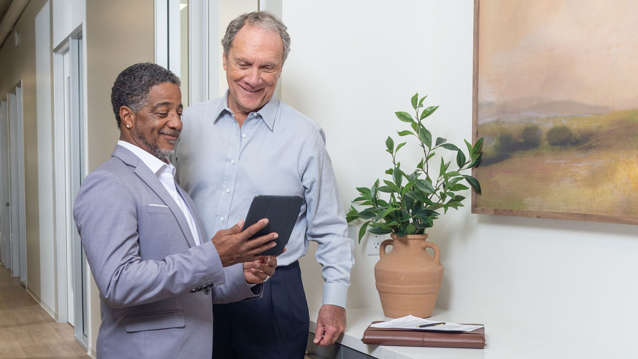 Two people learn about TruStage's financial information by looking at a tablet