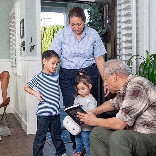 A mother is greeted by her children at the front door.
