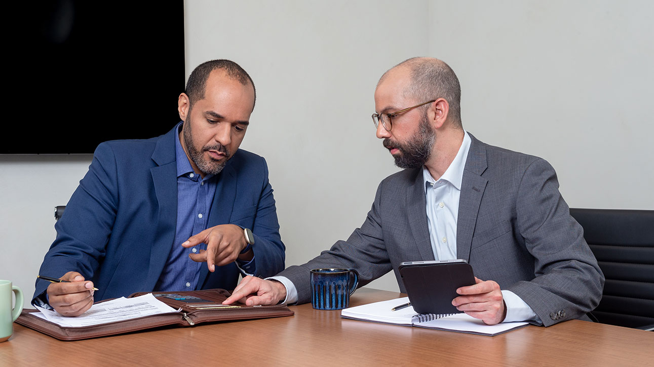 A couple people review TruStage business protection news while sitting at a table together