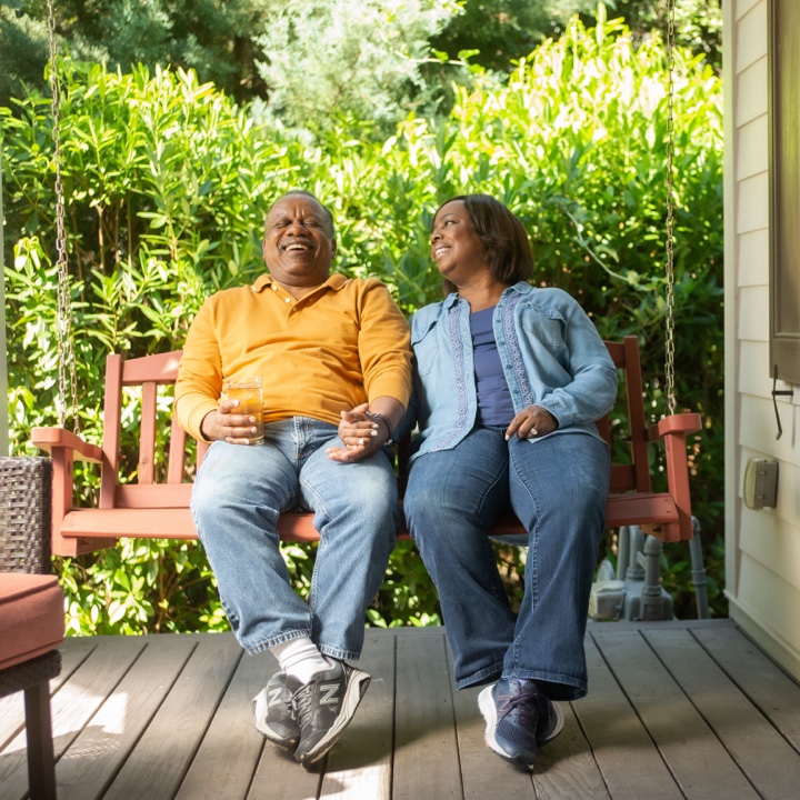 A happy couple on a porch swing having piece of mind thanks to their insurance policy