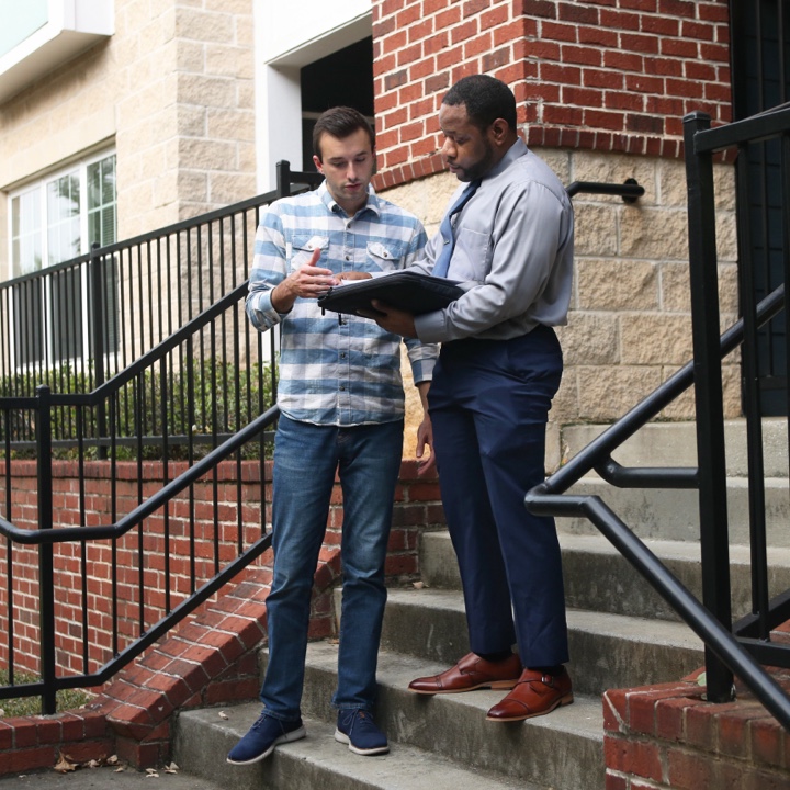A tenant discussing condo insurance with his insurance agent on the front steps of his condo unit
