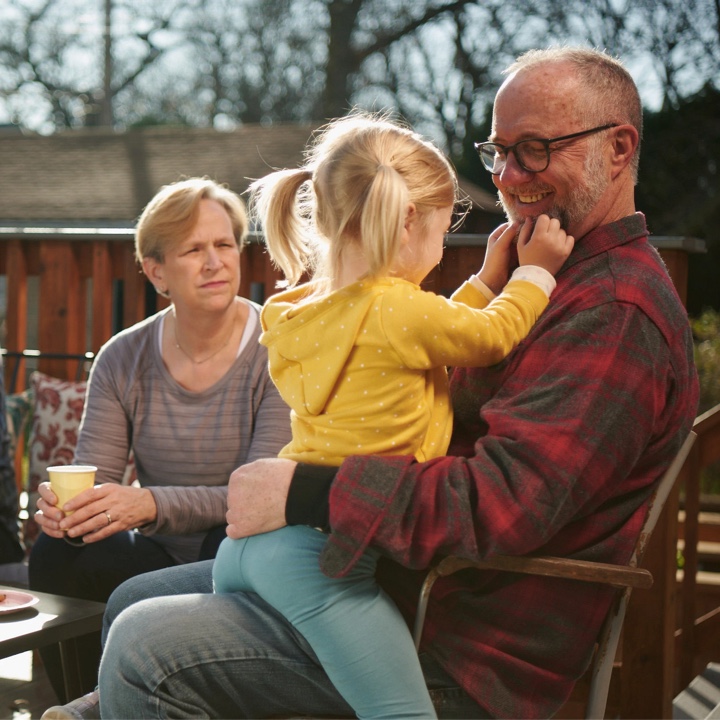 Grandparents at peace, thanks to their life insurance policy, play with their granddaughter outside on their deck
