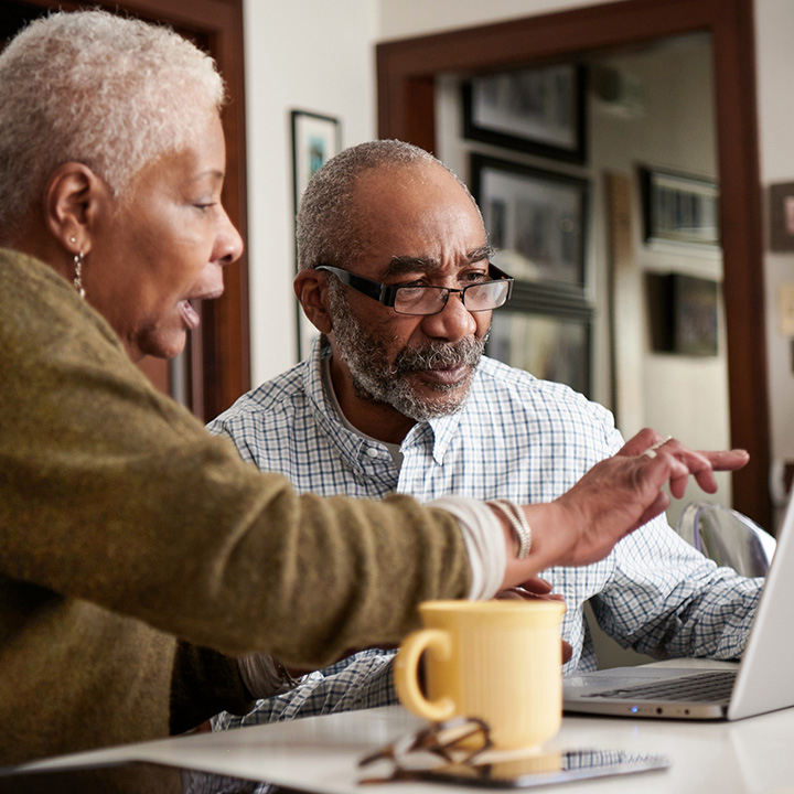 Husband and wife researching their life insurance options on a computer