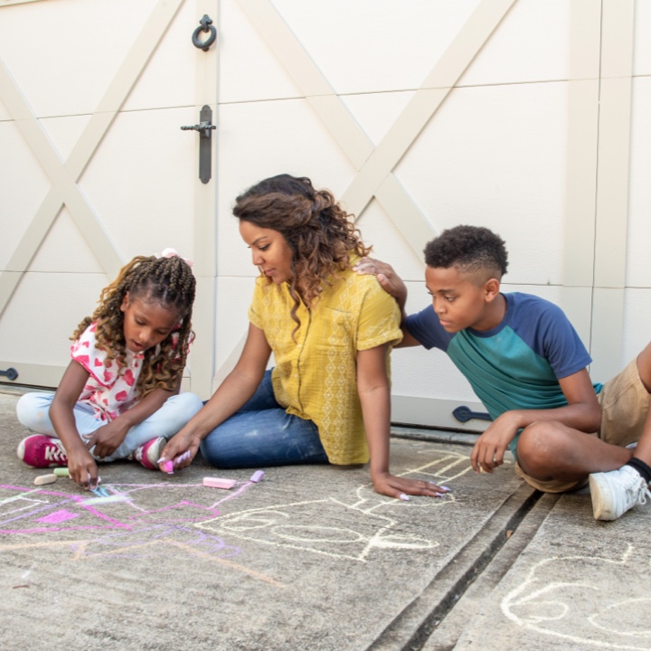 A young mom wonders about life insurance as she makes chalk drawings on her driveway with her kids