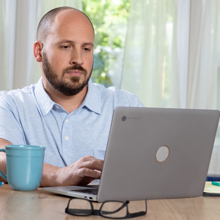 A man sitting at his table with laptop reviews his insurance coverage