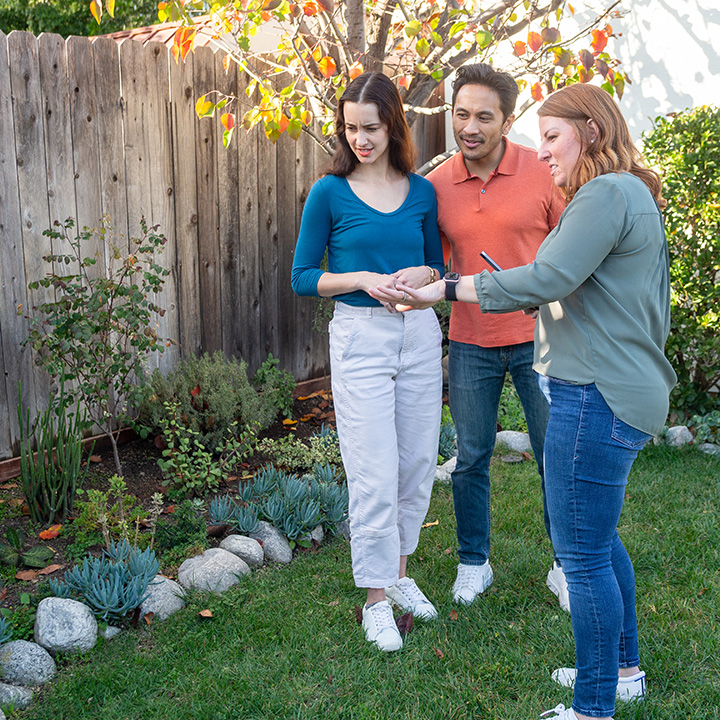 A couple and their realtor looking at landscaping