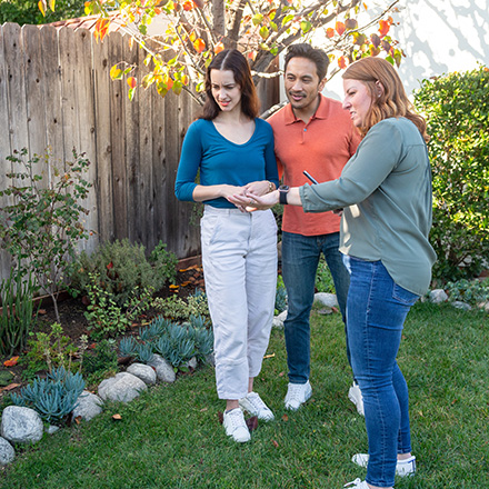A couple and their realtor looking at landscaping