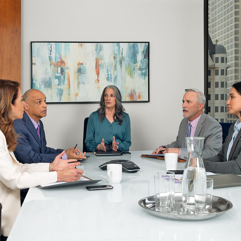 Five lending professionals in an office discuss Payment Guard Advantage benefits.