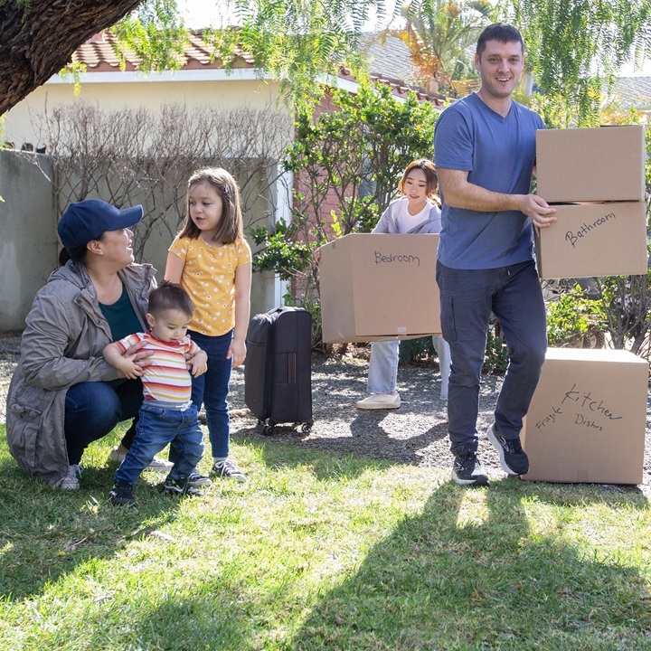 A mother, father, and children carry boxes into their new home after transferring their renters insurance to a new address.
