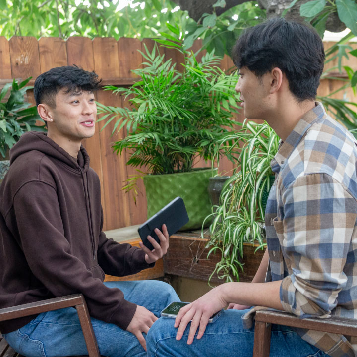 Two young men holding their phones and talking