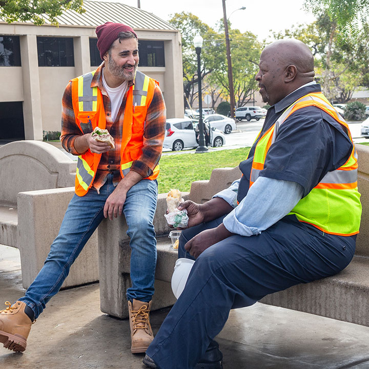 Two tow truck drivers eating outside on their lunch break are better protected by AD&D insurance from TruStage.