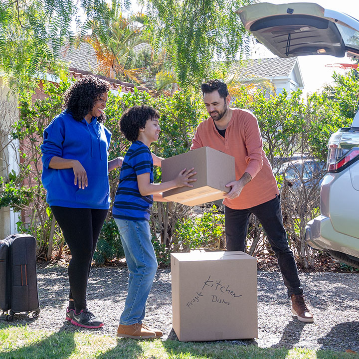 A young family loads boxes into their car have piece of mind provided by the TruStage Auto and Home Program.