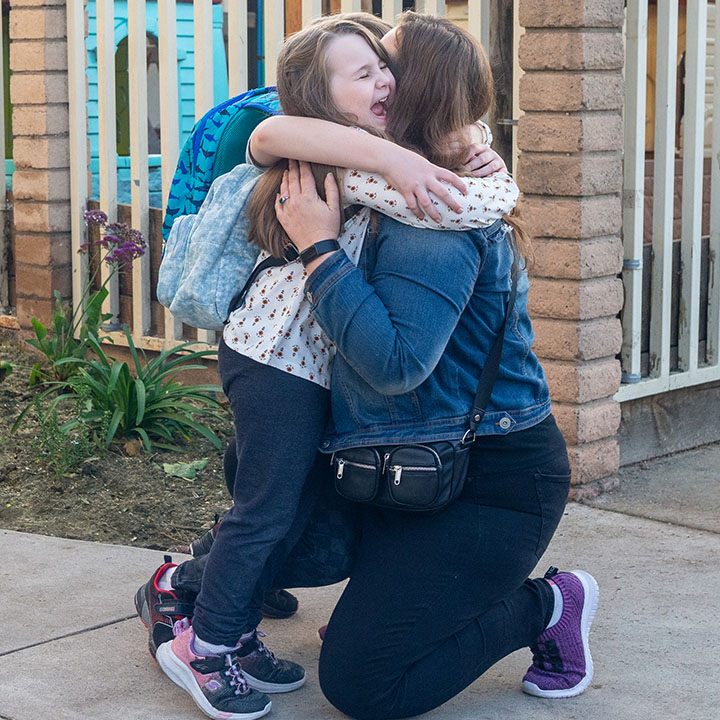 A mom hugs her daughter on the sidewalk after school is better protected by TruStage Life Insurance.