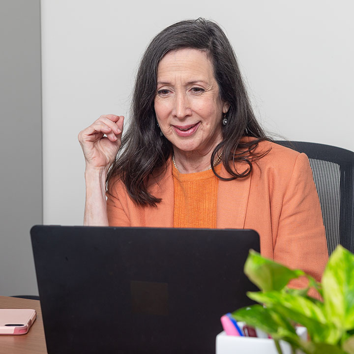 A woman seated at her desk is using her laptop to research information about her TruStage Loan.