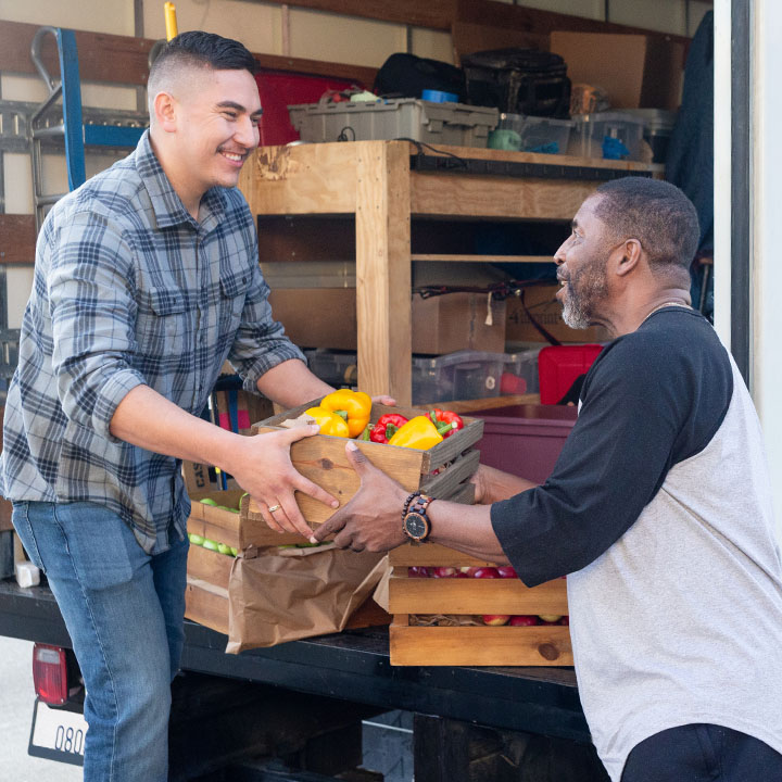 Two men are unloading groceries from the back of a delivery truck.