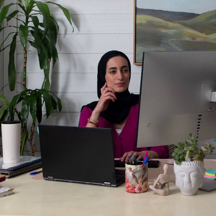 A woman looks at her computer screen while she works from home.