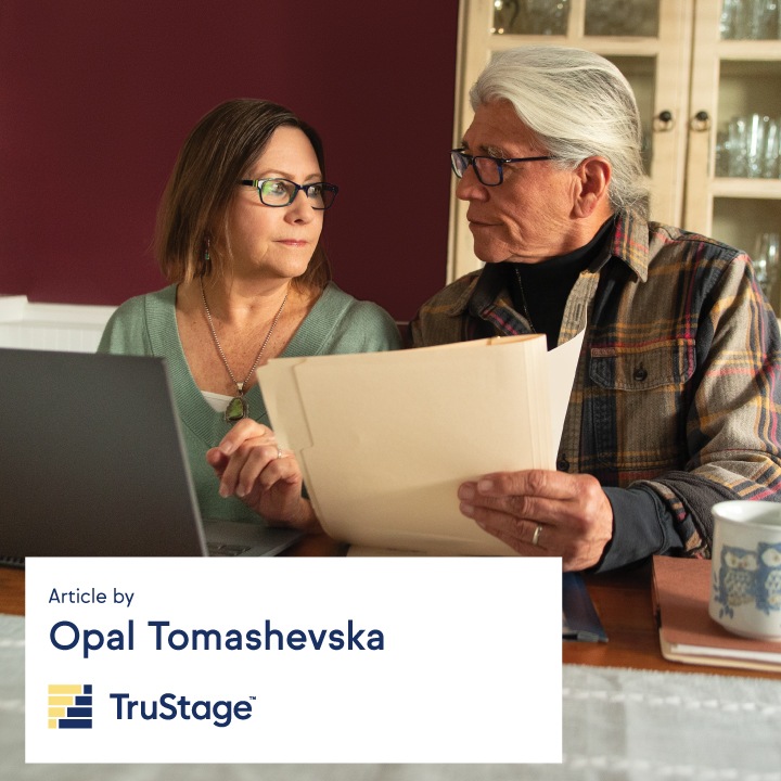 A husband and wife look through financial documents while sitting at a table.