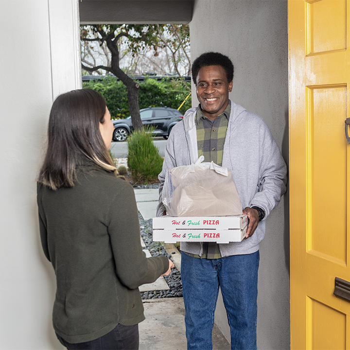 A delivery man drops off pizza at a house