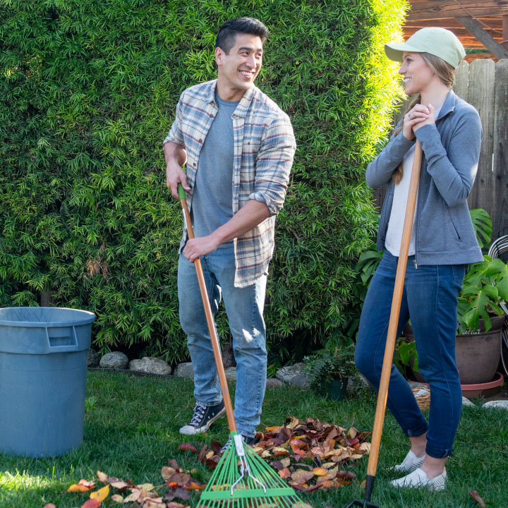 A husband and wife rake leaves in the yard while discussing how to make an inventory list.