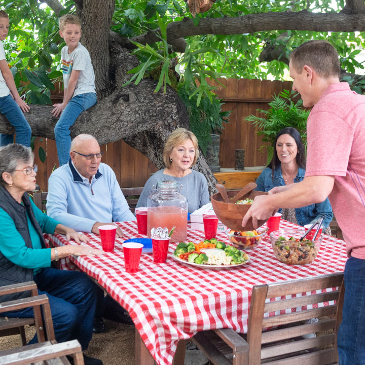 A family enjoying a meal outside, discussing their life insurance policies