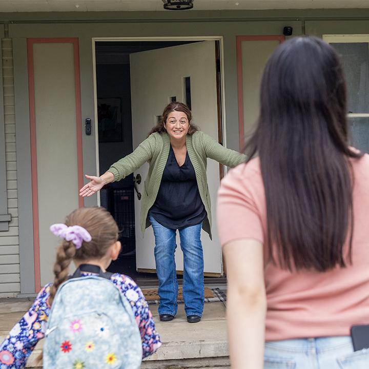A mother greeting her children at her door