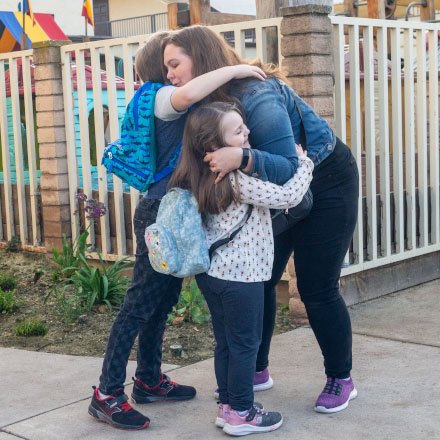 A mom hugs her two kids and is better protected by TruStage Life Insurance.