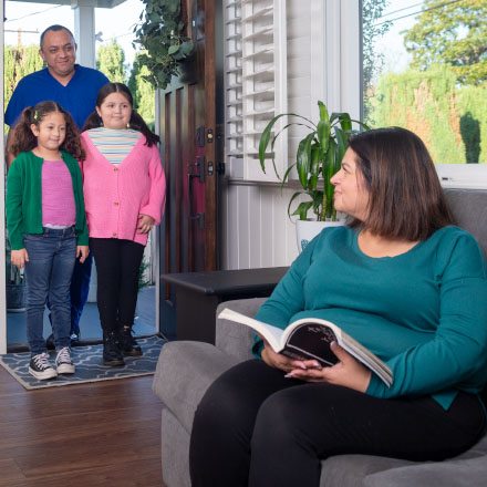 Two grandkids and grandpa greet grandma in her home protected by TruStage Insurance