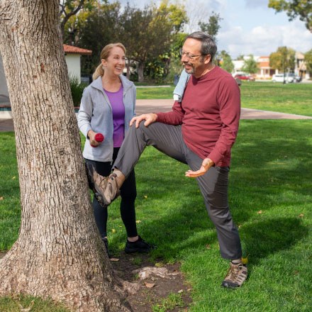 A woman and man discuss life insurance from TruStage while stretching in a park after their workout.