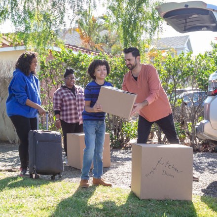 A young family loads boxes into their car that is protected with TruStage Insurance