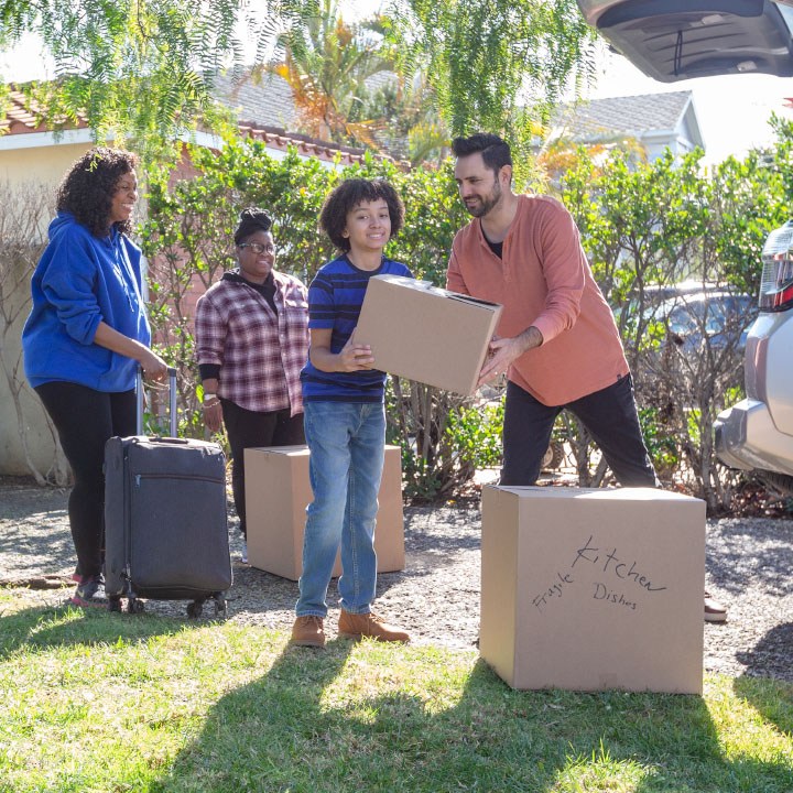 A young family loads boxes into their car that is protected with TruStage Insurance